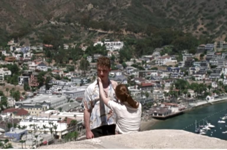 A couple overlooking a harbour town, from the Thinking About You video